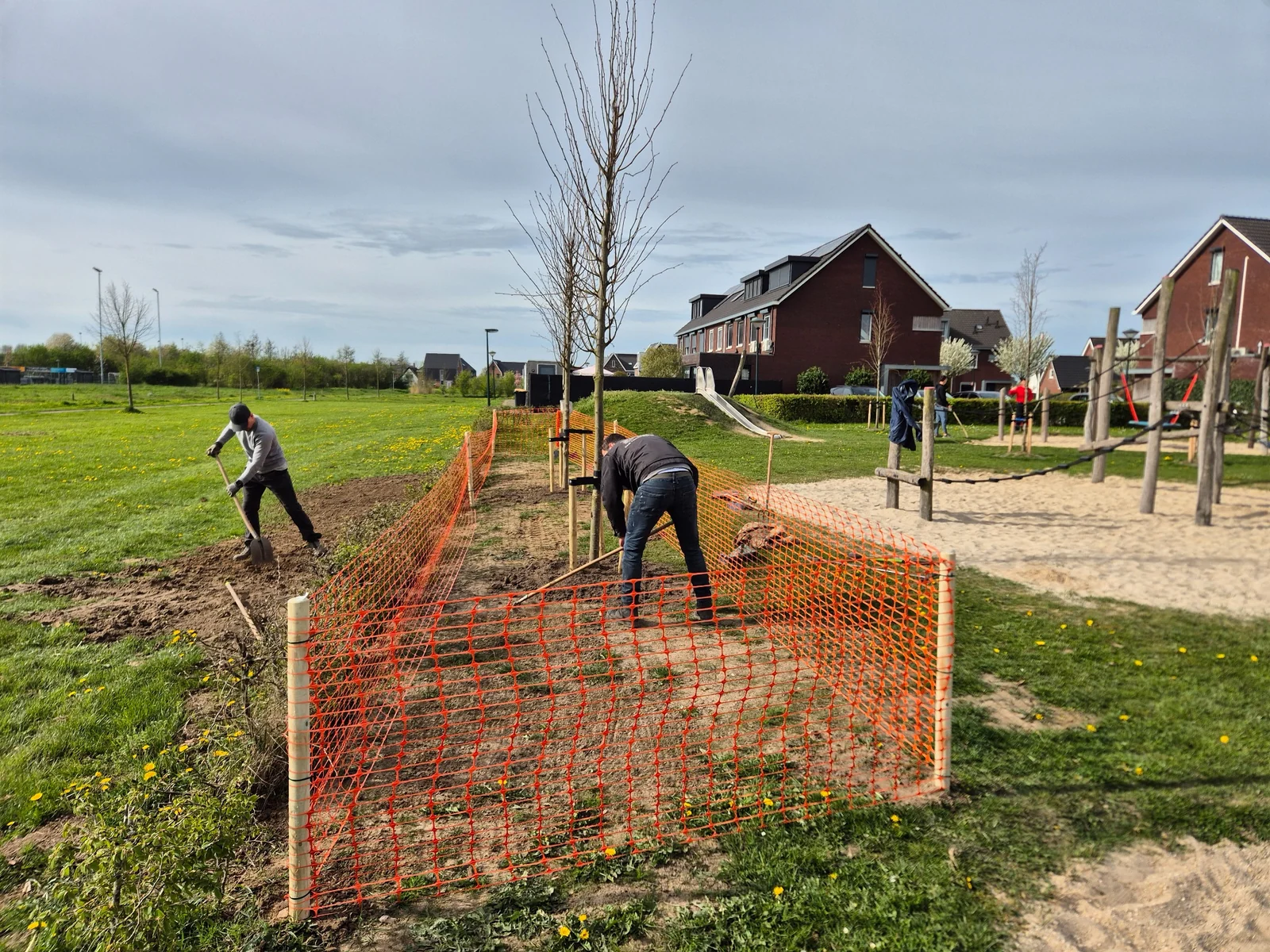 Buurtbewoners aan het werk bij de speeltuin, onder andere met onderhoud en bomen planten.
